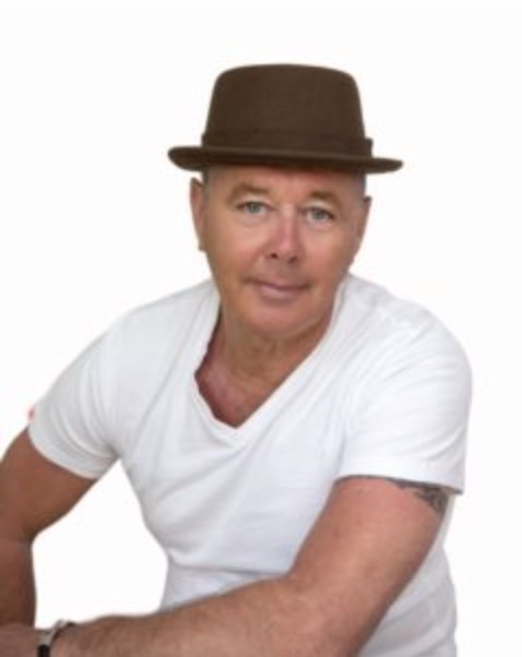 John Livings in a brown pork-pie hat and white T-shirt
